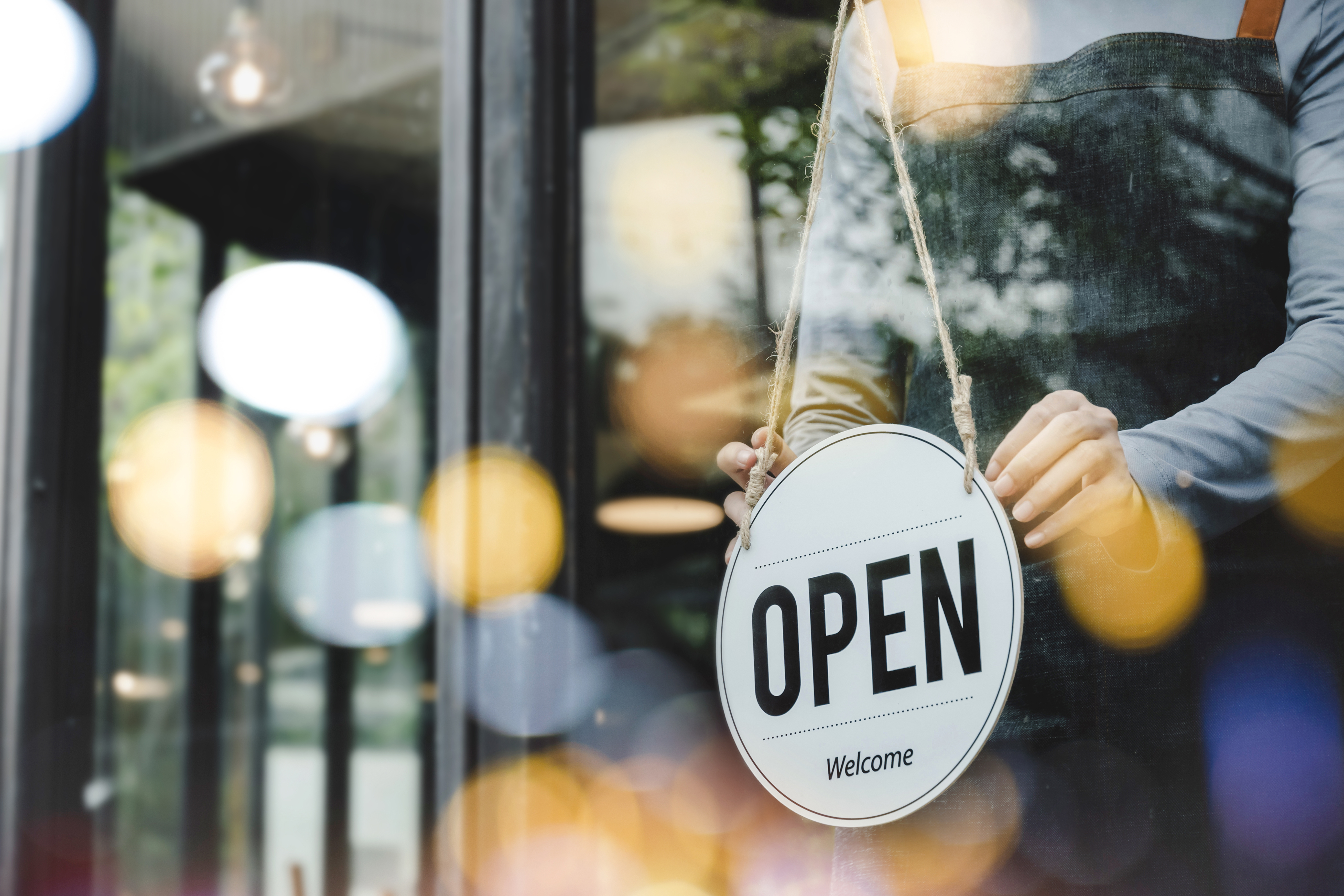 A shop owner hanging the open sign in the window